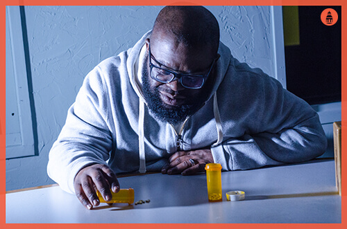 man with ambien addiction staring at pills on table