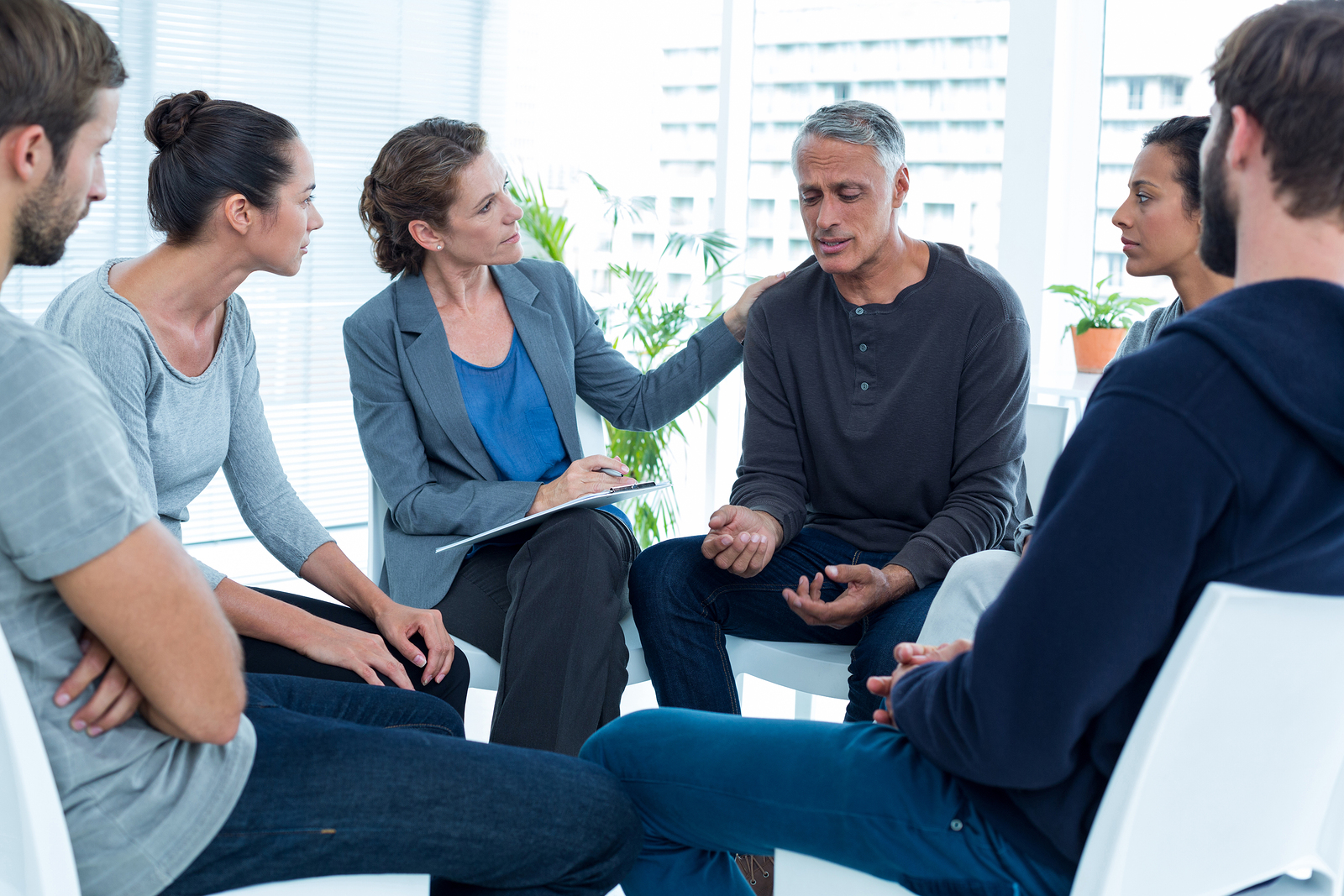 Concerned woman comforting another in rehab group at a therapy s