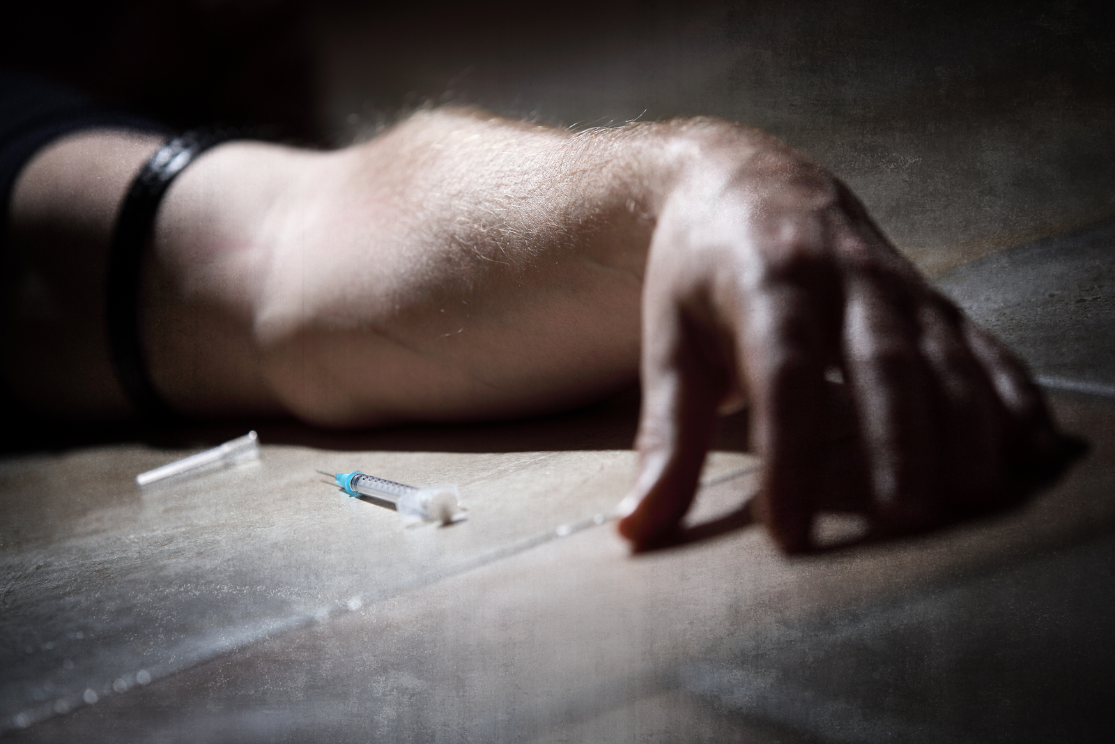 Drug addict with syringe lying down on the floor concept for sel