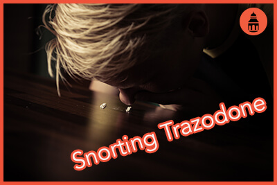 Addicted teenage boy snorting white powder off a table sniffing up the lines of narcotic with his nostrils